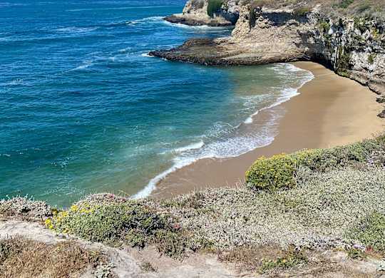 A beach with a cliff and ocean in the background at Westmont Place Townhomes Apartments, California, 95060