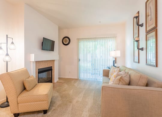 A living room with a fireplace, two couches, and a chair. at Palm Court Apartments, Salinas, 93906