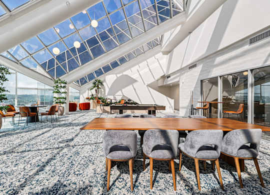 A modern dining room with a glass ceiling and a long wooden table at 7 West 7th Apartments, Ohio