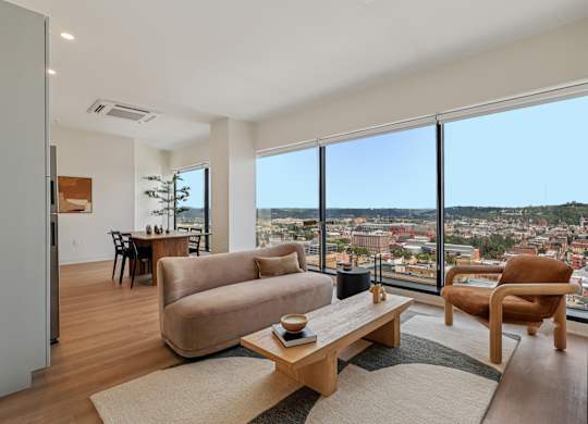 A living room with a couch, chair, and table with a view of the city at 7 West 7th Apartments, Ohio, 45202