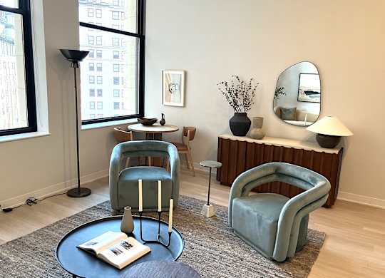 A living room with a blue chair and a round table with a book on it.