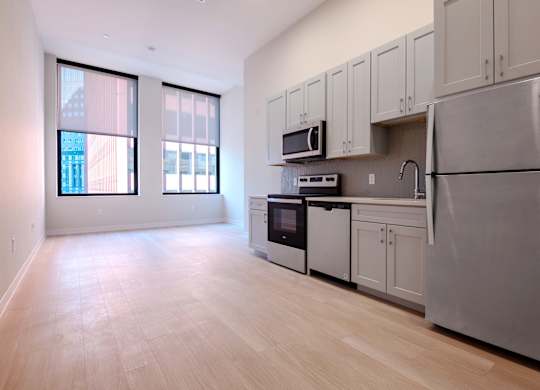 A kitchen with a refrigerator, microwave, oven, and sink.