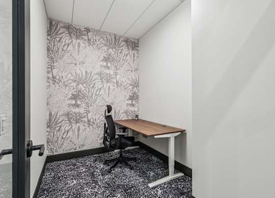 A small room with a desk and a plant pattern wallpaper. at LiveWell Apartments, Pittsburgh 15222