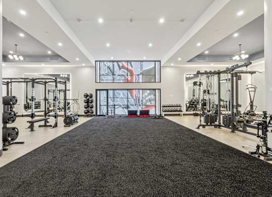 A spacious gym with a variety of equipment and a large mirror on the wall. at LiveWell Apartments, Pennsylvania