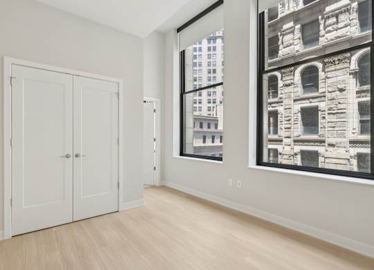 A room with a white door and a large window with a black and white picture on the wall at LiveWell Apartments, Pittsburgh, PA