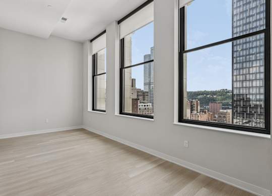 A large empty room with a view of the city through the windows at LiveWell Apartments, Pittsburgh 15222