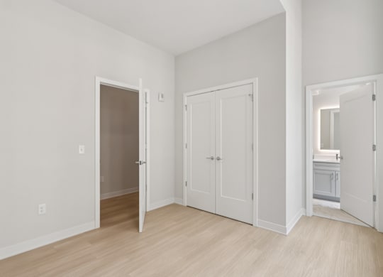 A white room with a wooden floor and three doors at LiveWell Apartments, Pittsburgh