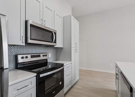 A kitchen with a stove, oven, microwave, and cabinets. at LiveWell Apartments, Pittsburgh 15222