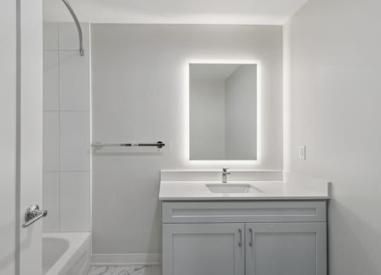 A white bathroom with a sink, mirror, and bathtub at LiveWell Apartments, Pennsylvania, 15222