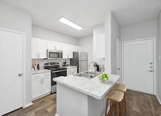 A kitchen with white cabinets and a marble island.