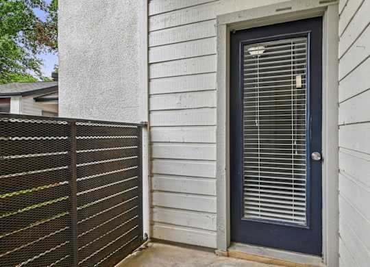 A blue door with a window above it and a fence to the left.
