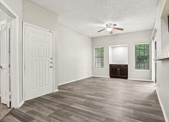 A room with a white door and a ceiling fan.
