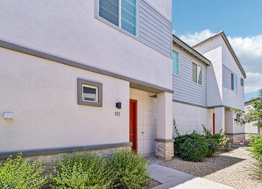 Baseline on 16th townhome with a red door and a small window on the side.