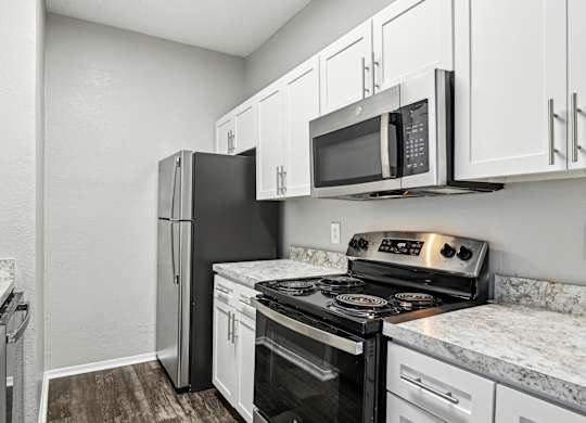 A kitchen with a black refrigerator, black stove, and white cabinets.