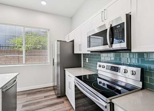 Baseline on 16th townhome kitchen with a stove, refrigerator, and microwave.