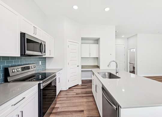 Baseline on 16th townhome modern kitchen with white cabinets and a wooden floor.
