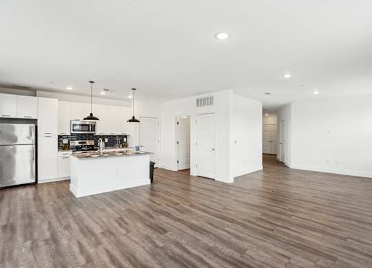 A modern kitchen with wooden floors and white cabinetry.