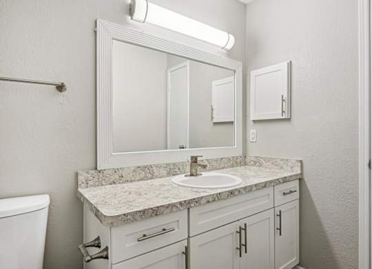 A bathroom with a marble countertop and white fixtures.