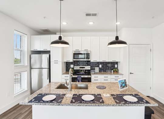 A modern kitchen with a granite countertop and stainless steel appliances.