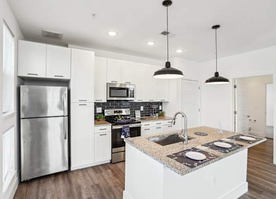 A modern kitchen with a granite countertop and stainless steel appliances.