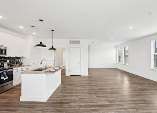 A modern kitchen with wooden floors and white cabinetry.