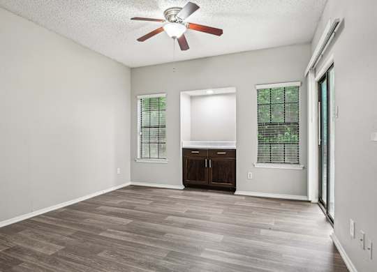 A room with a ceiling fan and wooden flooring.
