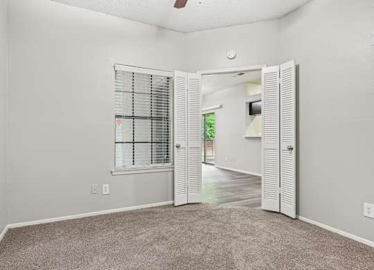 A room with a carpeted floor and a window with blinds.