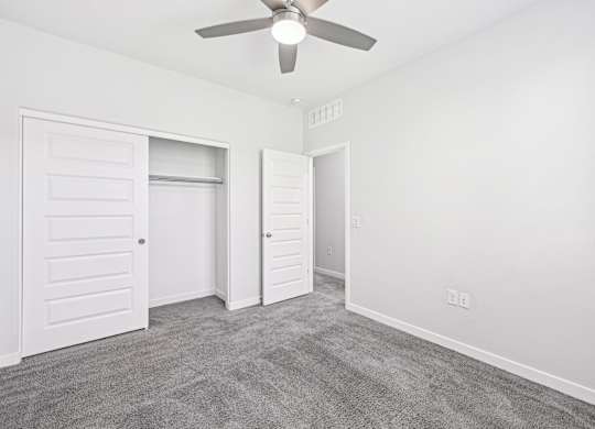 Baseline on 16th townhome bedroom with a ceiling fan and two doors.