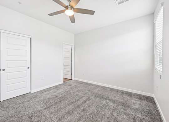 Baseline on 16th townhome room with a ceiling fan and carpeted floor.