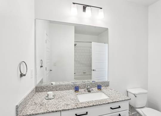 A bathroom with a granite countertop and white fixtures.