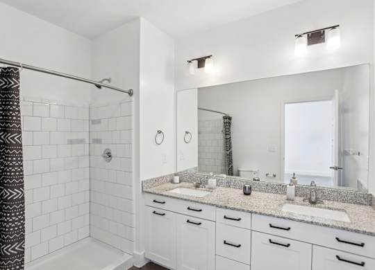 A bathroom with a white tile shower and a marble countertop.