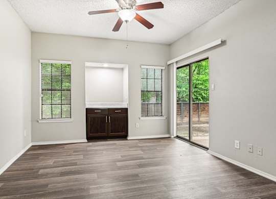 A room with a ceiling fan and sliding glass doors.