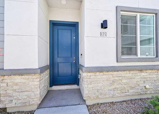 Baseline on 16th townhome entrance with a blue door is on the left side of a house with a stone wall.
