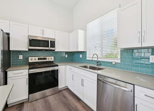 Baseline on 16th townhome kitchen with white cabinets and a stainless steel dishwasher.