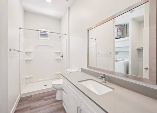 A white bathroom with a toilet, sink, and mirror.