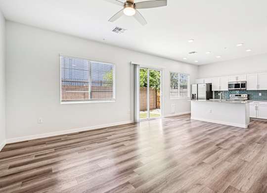 Baseline on 16th townhome spacious kitchen and living room with wood flooring and white walls.
