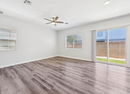 Baseline on 16th townhome room with a ceiling fan and sliding glass doors.