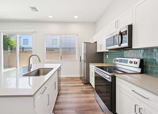 Baseline on 16th townhome kitchen with white cabinets and a wooden floor.