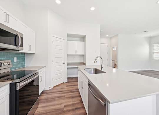 Baseline on 16th townhome modern kitchen with white cabinets and a wooden floor.