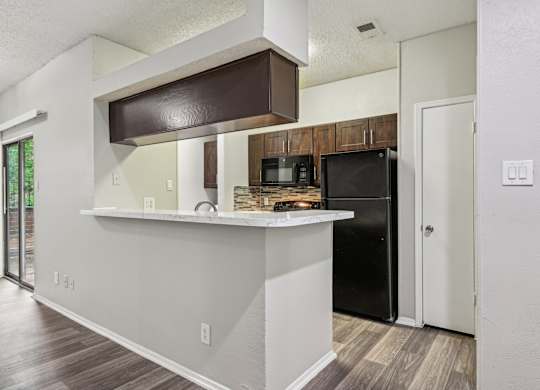 A kitchen with a black refrigerator and a white counter.