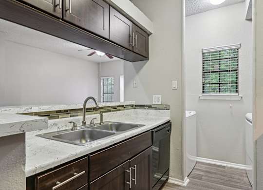 A kitchen with a marble countertop and dark wood cabinets.