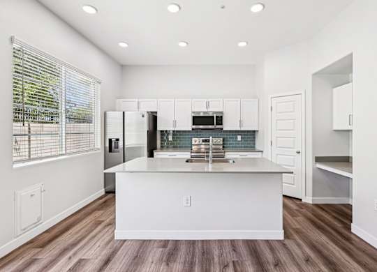 Baseline on 16th townhome kitchen with white cabinets and a wooden floor.