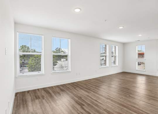 A large empty room with wooden floors and windows.