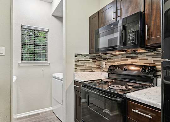 A kitchen with a black stove top oven and a black microwave above it.