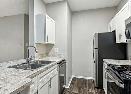 A kitchen with a black refrigerator and white cabinets.