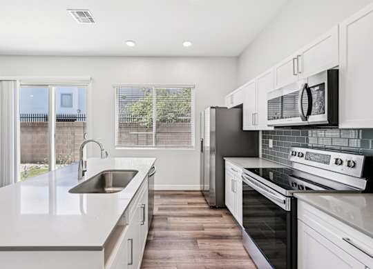 Baseline on 16th townhome modern kitchen with white cabinets and stainless steel appliances.