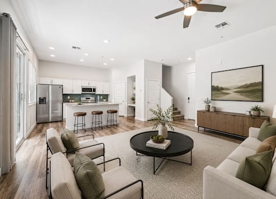 A modern living room with a kitchen in the background.