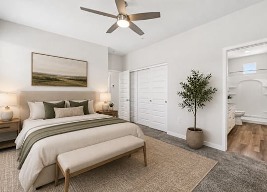 A bedroom with a bed, a bench, a ceiling fan, and a painting on the wall.