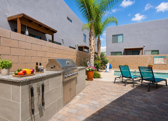 A modern outdoor kitchen with a grill and seating area.