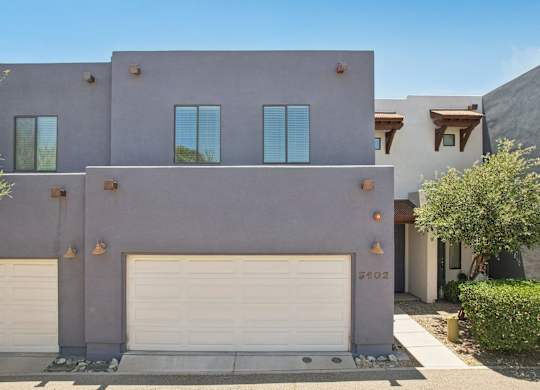 A modern house with a grey facade and white garage doors.